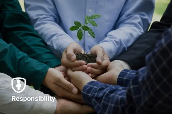 Hands holding soil with a small plant, symbolizing teamwork and responsibility.