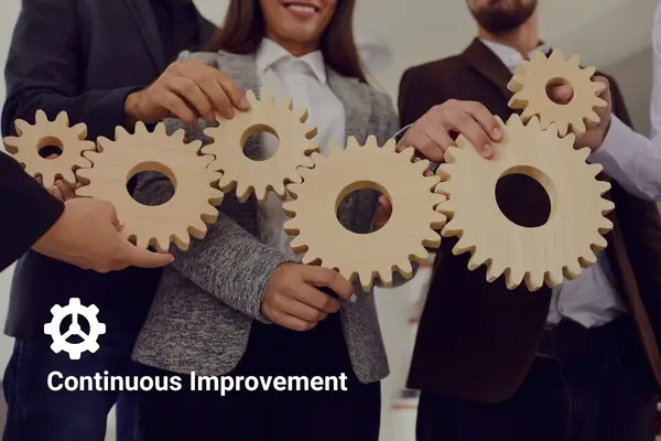 Team holding wooden gears representing collaboration and continuous improvement.