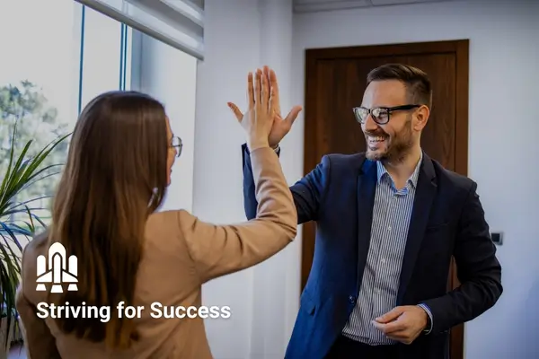 High-five between colleagues in office, celebrating success.